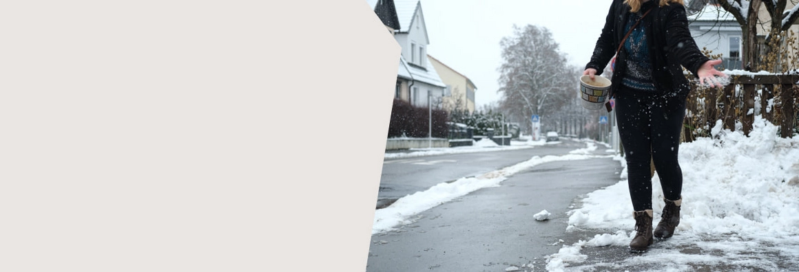 Person streut gegen Glätte