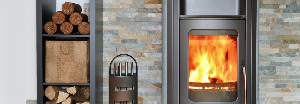 Ein brennender Kaminofen mit Kaminbesteck.