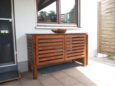 Holzschrank mit Lamellentüren auf einer Terrasse