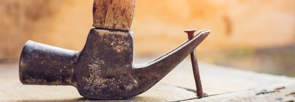Hammer zieht Nagel aus Holz