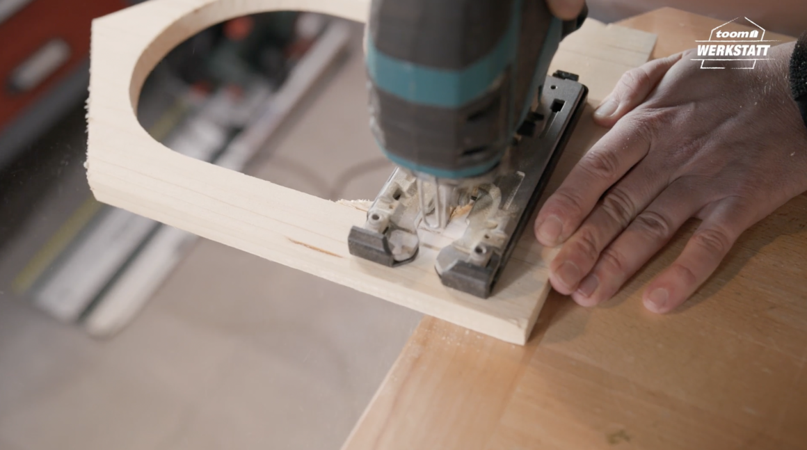 Person sägt mit Stichsäge Kreis in Holzbrett