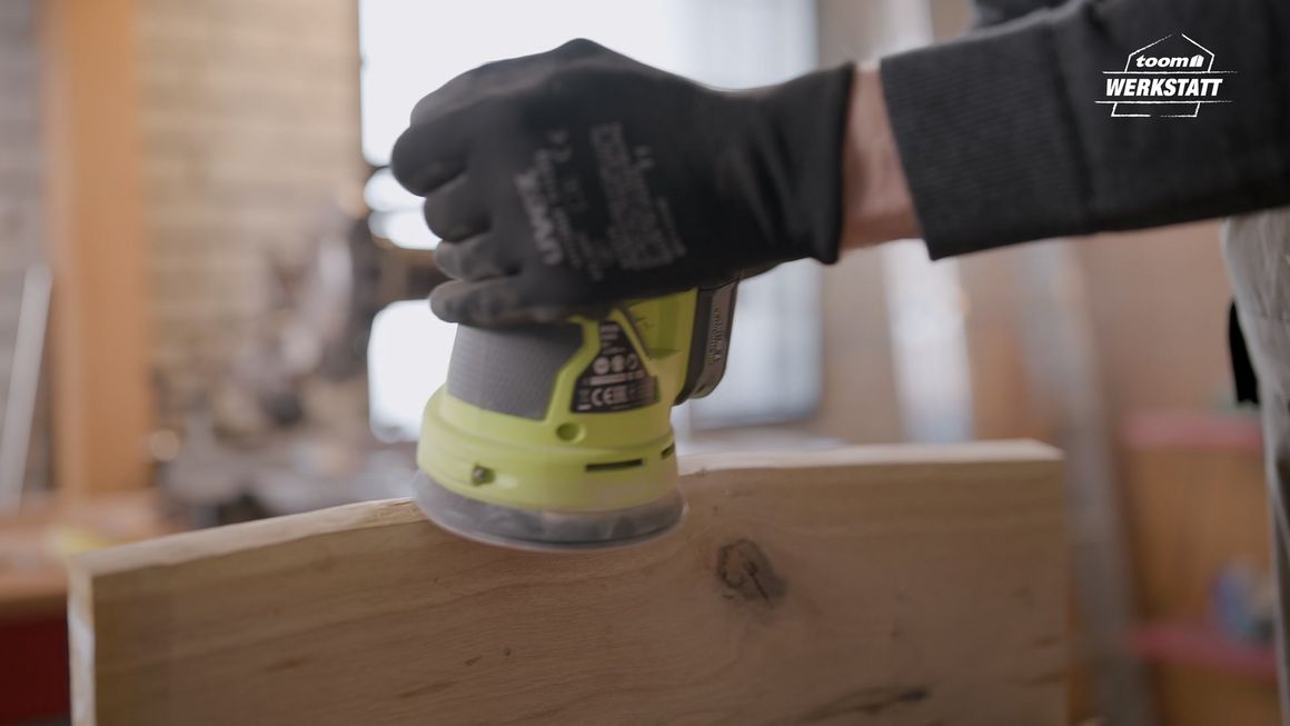 Person schleift Holz mit einem Schwingschleifer