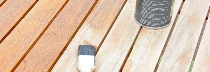 Holzlasur und Pinsel auf einem Gartentisch