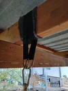 Aufhängung mit Gurt und Karabiner an einem Holzbalken.