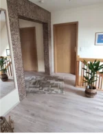 Heller Flur mit zwei Türen und Treppengeländer.