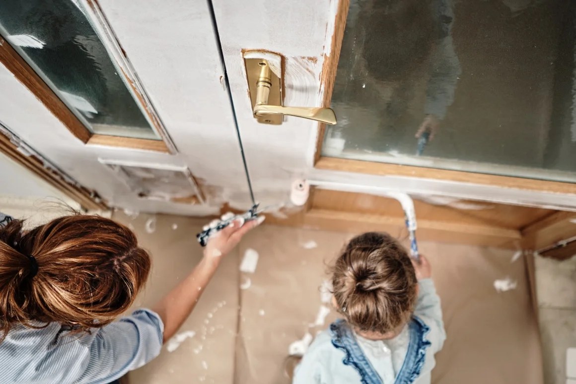 Zwei Personen streichen eine Tür mit Farbe