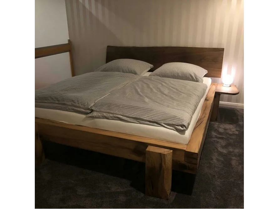 Ein Bett aus dunklem Holz mit Bettzeug.