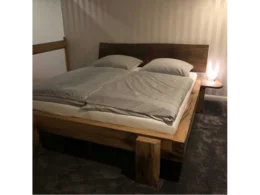 Ein Bett aus dunklem Holz mit Bettzeug.