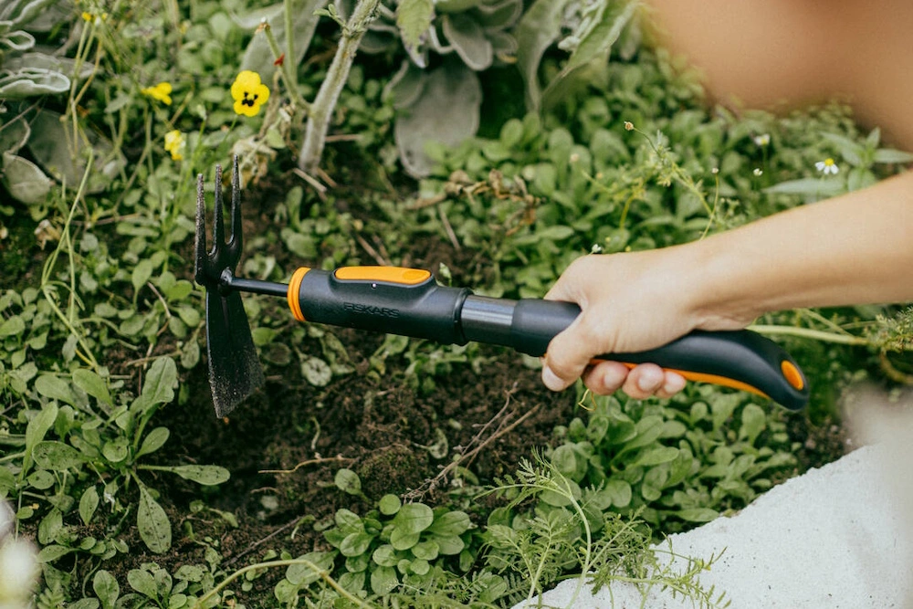 Eine Person nutzt ein Fiskars Werkzeug im Garten