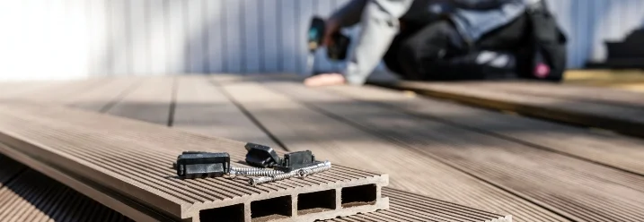 Person verlegt Terrassendielen mit Akkuschrauber