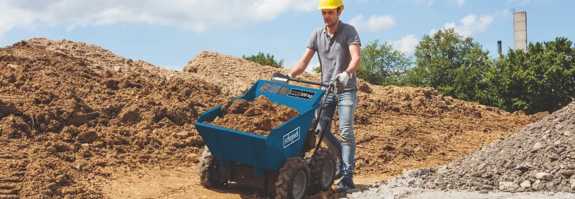 Person transportiert Erde mit motorisierter Schubkarre