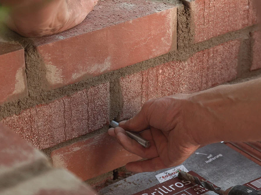 Person befestigt Gewindestange in Mauerwerk