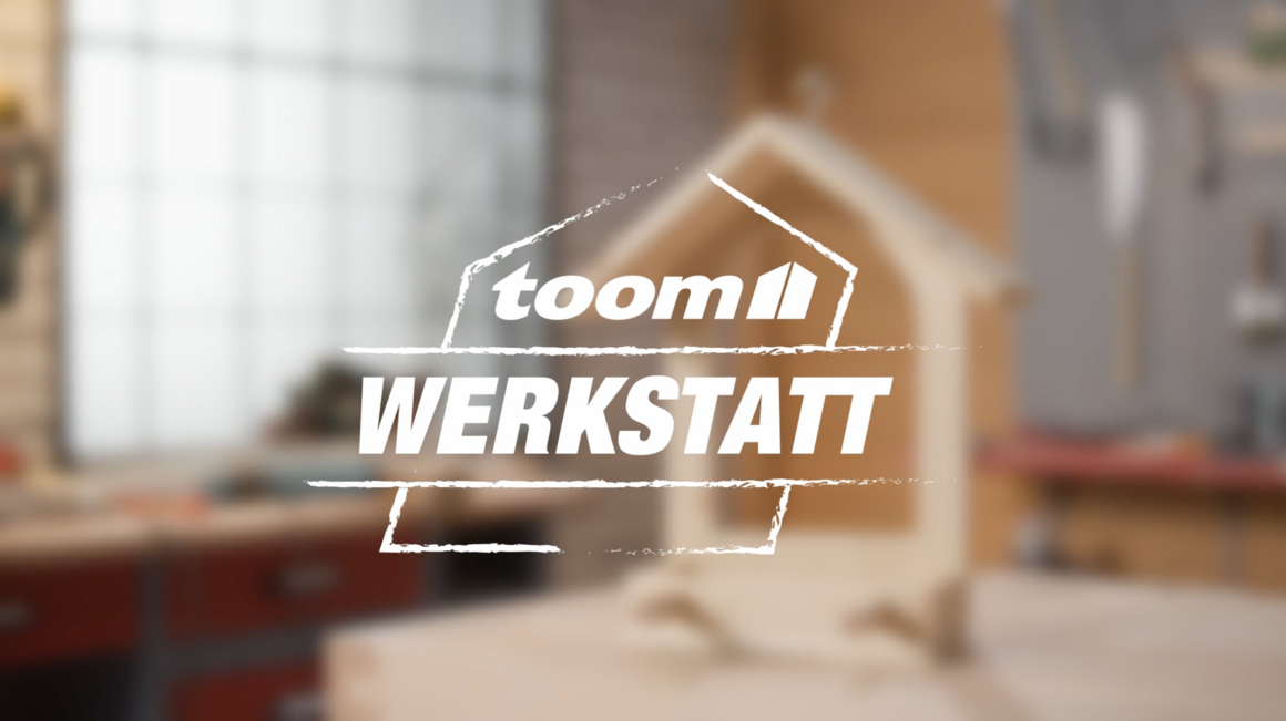 toom Werkstatt Logo mit unscharfem Vogelhaus im Hintergrund