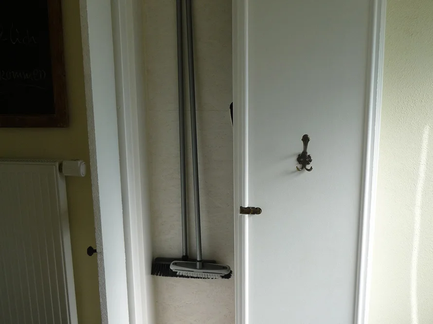 Besen und Handfeger in einem Wandschrank