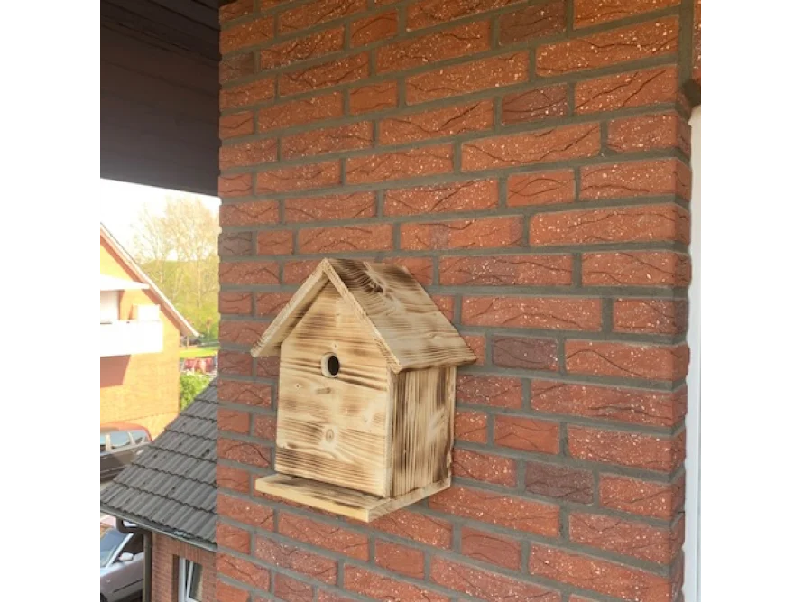 Vogelnistkasten aus Holz an Backsteinwand