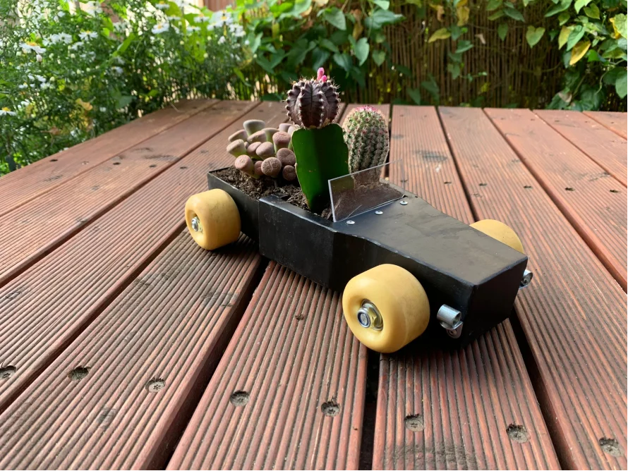 Schwarzer Übertopf in Form eines Autos mit Sukkulenten bepflanzt