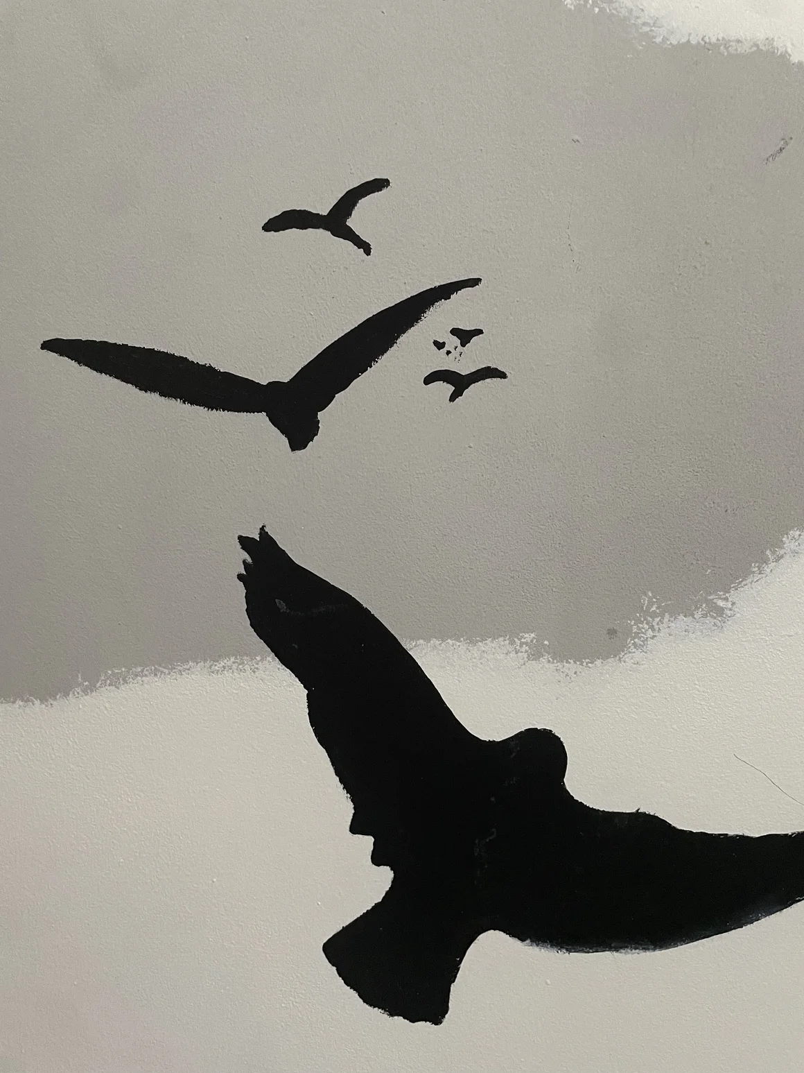 Wandmalerei mit schwarzen Silhouetten von Vögeln im Flug.