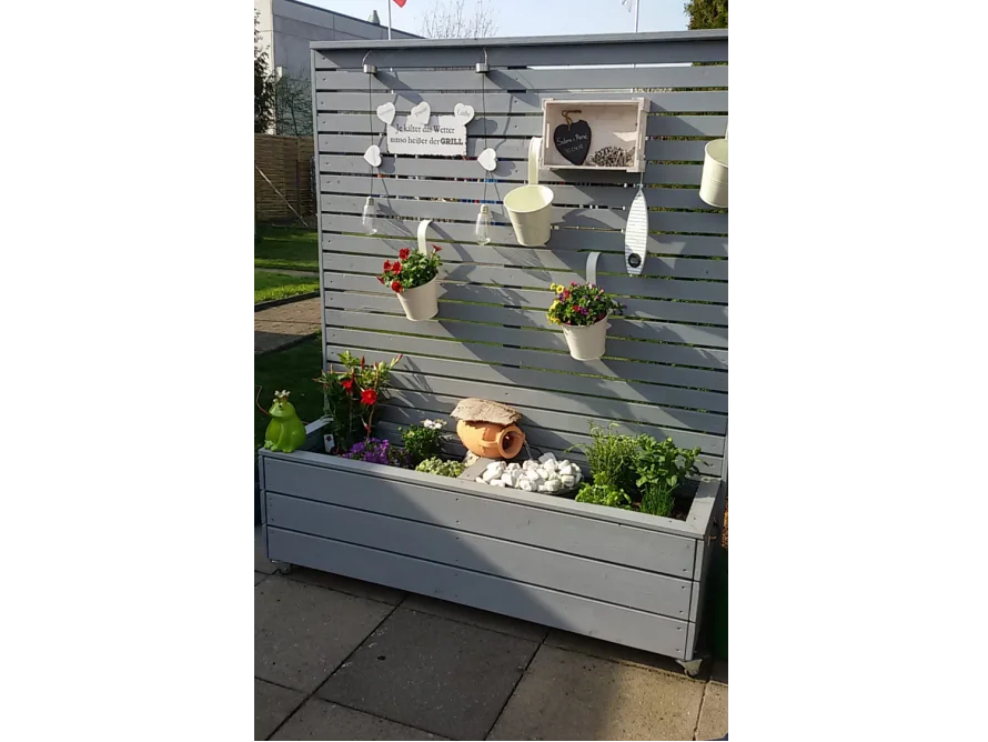 Grauer Holzkasten mit Deko und Blumen