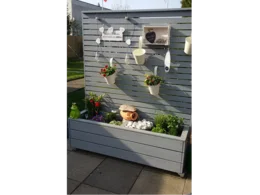 Grauer Holzkasten mit Deko und Blumen