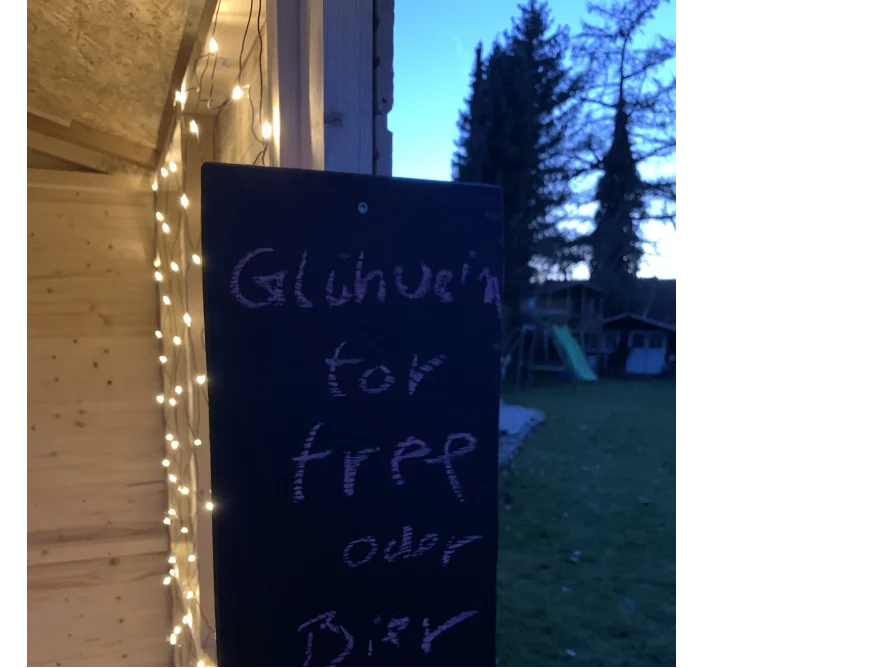 Schild mit Lichterkette an Holzwand