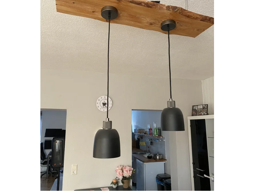 Zwei schwarze Hängelampen an Holzbalken