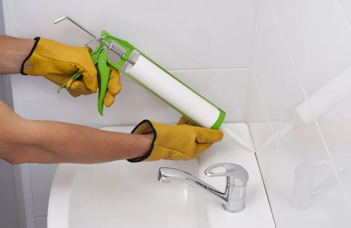 Person trägt Silikon mit Kartuschenpistole auf