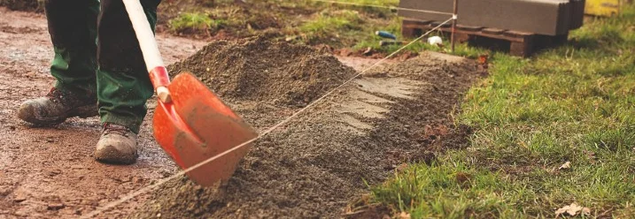 Person verteilt mit Schaufel Kies