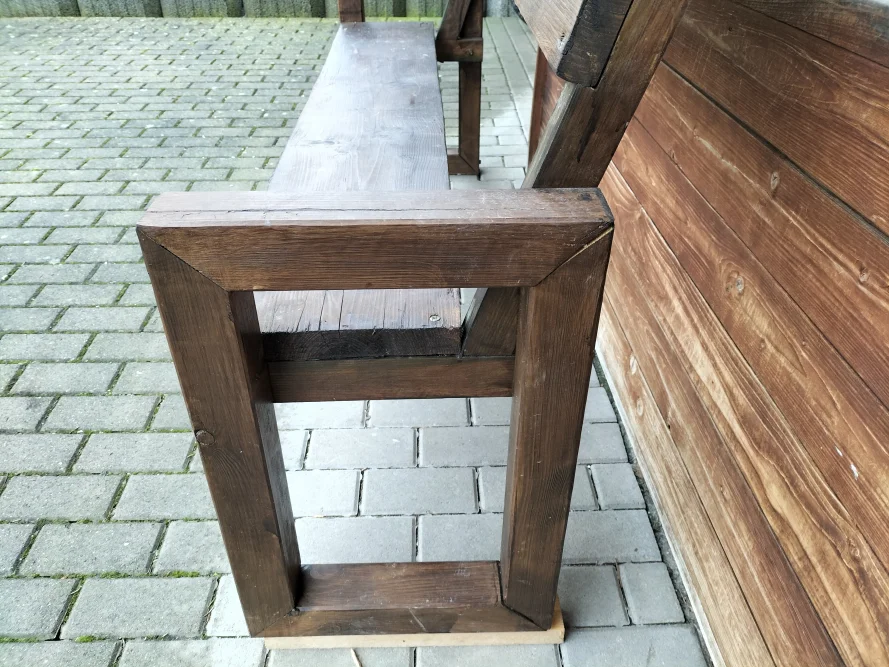 Ecke einer Holzbank aus dunklem Holz