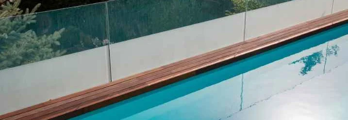 Sichtschutz aus Glas an einem modernen Swimmingpool mit Holzrand