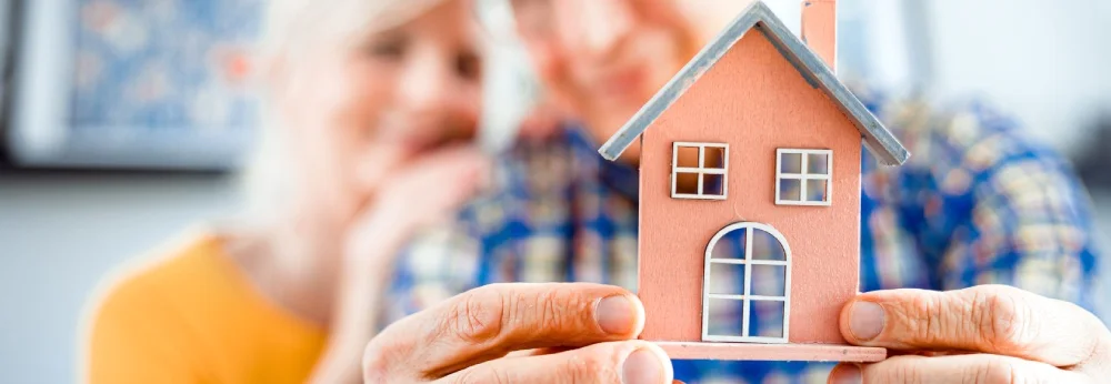 Zwei Menschen halten ein kleines Modellhaus in den Händen.