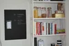 Ein weißes Regal mit Kochbüchern und einer schwarzen Magnettafel