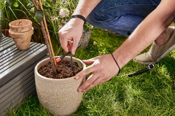 Person bringt Schlauch an Blumentopf an