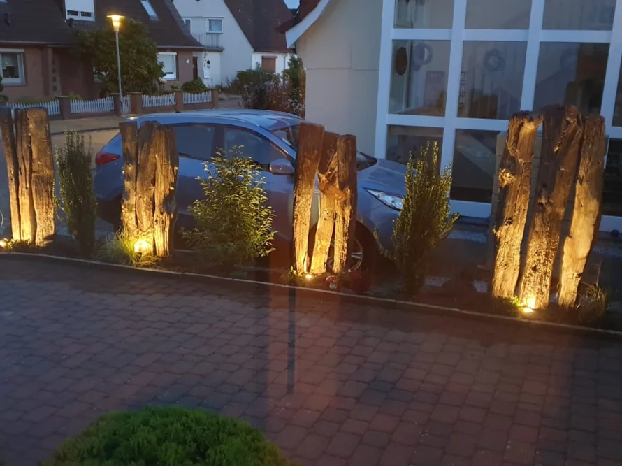 Einfahrt mit beleuchteten Holzpfählen