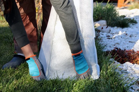 Person beim Überstülpen eines Frostschutzvlies