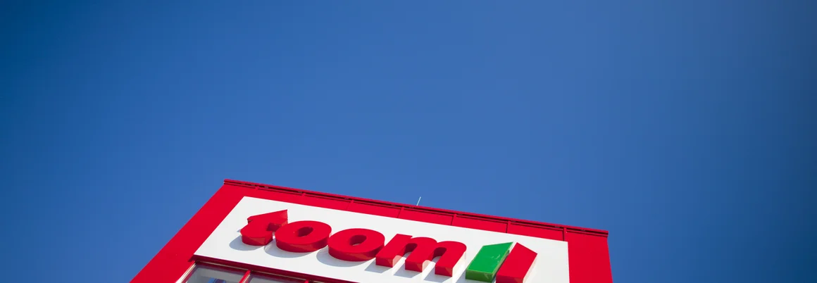 Rote Fassade eines Geschäfts mit Firmenlogo vor blauem Himmel