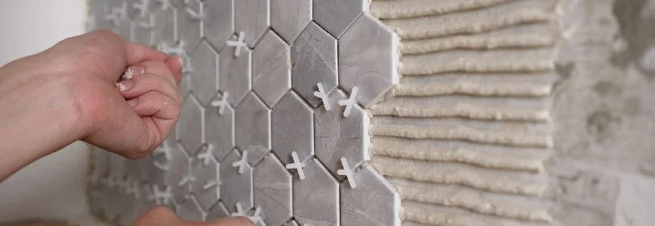 Person bringt sechseckige Fliesen an