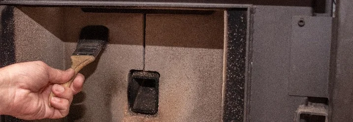 Person reinigt Ofen mit Bürste