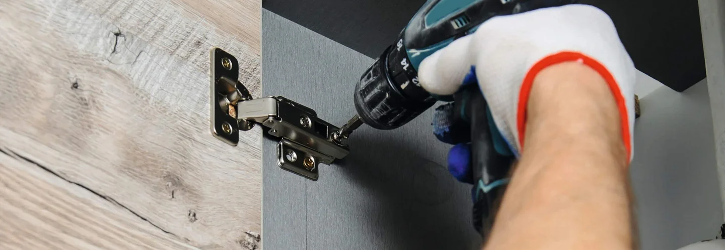 Person montiert Scharnier mit Akkuschrauber.