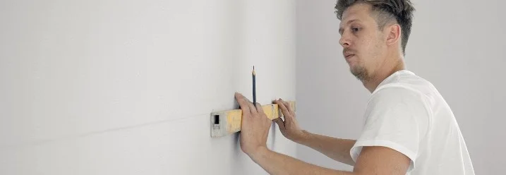 Person verwendet Wasserwaage an Wand