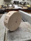 Ein bearbeitetes, polygonales Holzstück mit Löchern liegt auf einer Tischkreissäge.