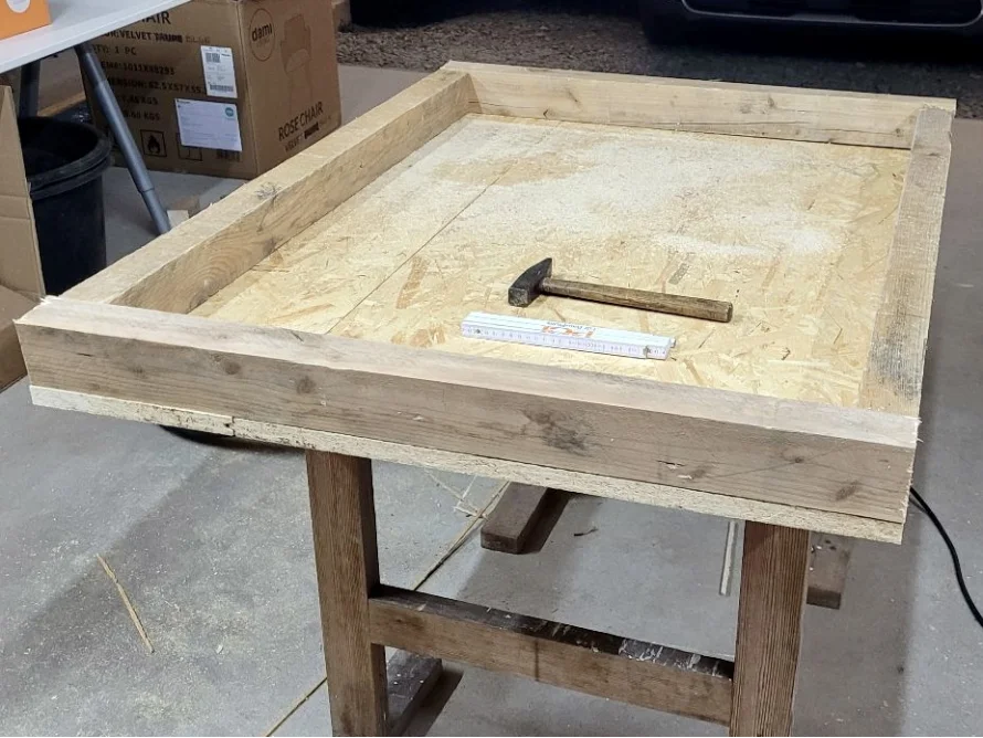 Holzrahmen auf einem Tisch mit Hammer