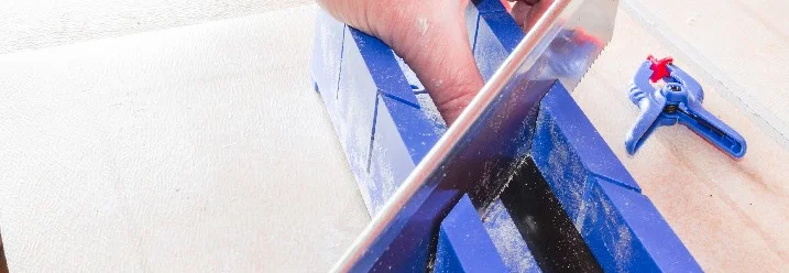 Person sägt Holz mit Gehrungslade.