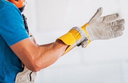Schutzhandschuhe Arbeiter zieht Schutzhandschuhe an.