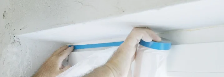 Person bringt Malerkrepp an Fenster an