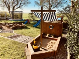 Spielplatz im Garten mit großem Sandkasten in Form eines Schiffes