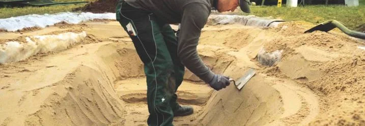 Person formt Sand mit Kelle