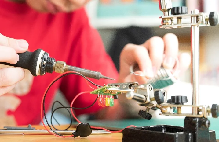 Person lötet mit Lötkolben eine Platine.