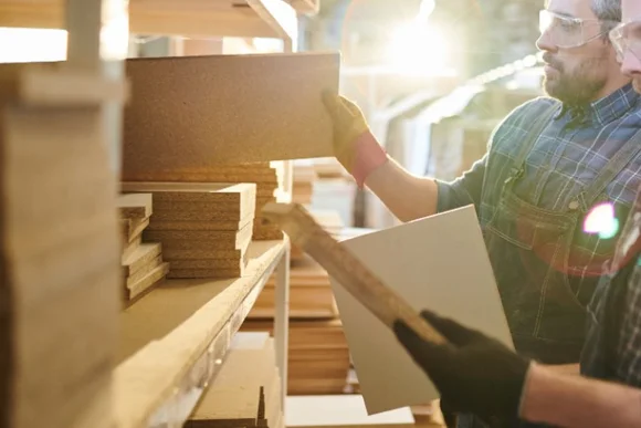 Zwei Personen begutachten Holzplatten im Lager.