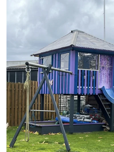 Spielhaus aus Holz mit Rutsche und Schaukel