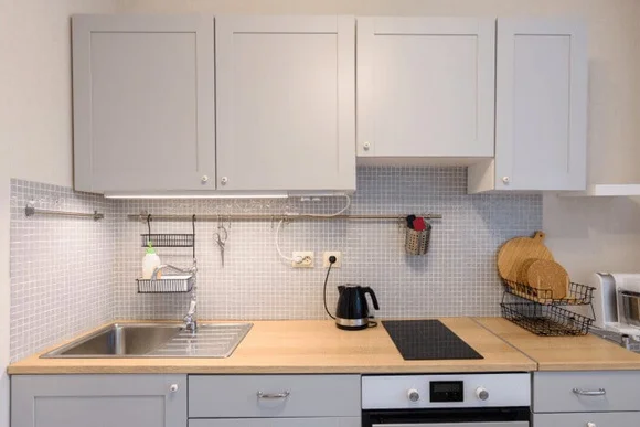 Moderne Küche mit grauen Schränken und Holzarbeitsplatte